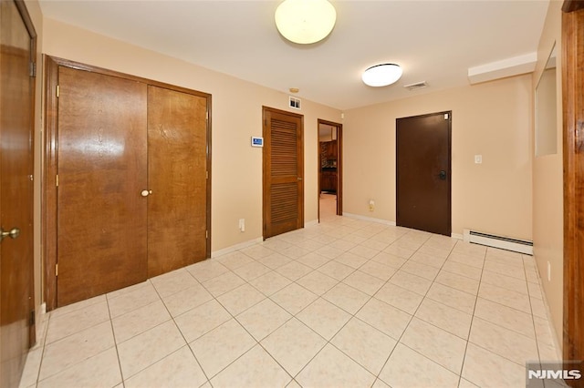 unfurnished bedroom featuring light tile patterned floors, visible vents, baseboard heating, and multiple closets