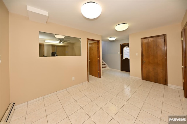 unfurnished room with baseboards, ceiling fan, stairway, light tile patterned floors, and baseboard heating