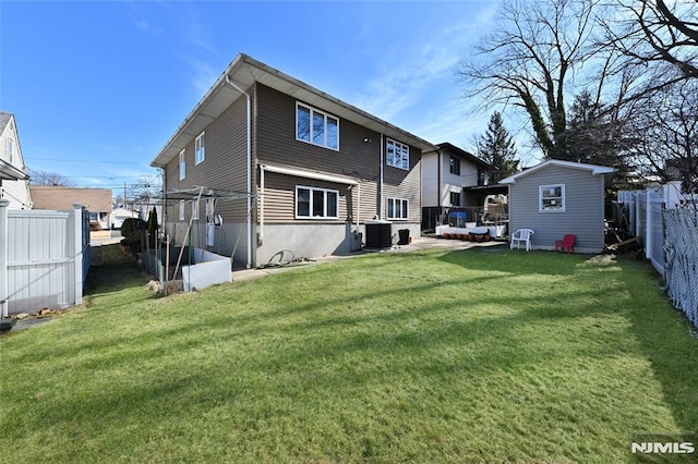 rear view of property with a yard, central air condition unit, an outdoor structure, and a fenced backyard