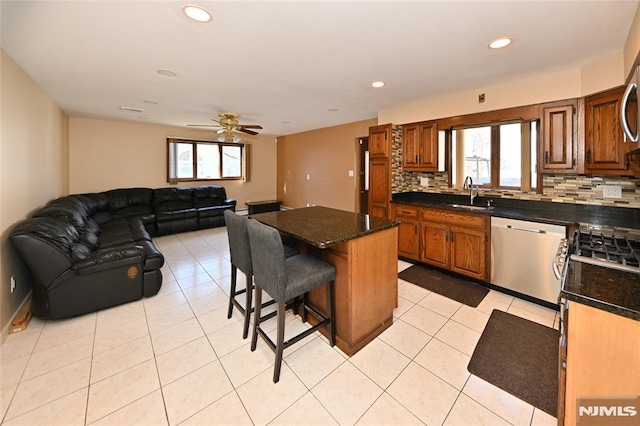 kitchen with a sink, dishwasher, tasteful backsplash, a kitchen bar, and a center island