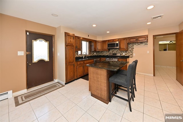 kitchen featuring visible vents, a sink, stainless steel appliances, light tile patterned floors, and decorative backsplash