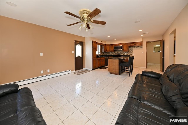 living room featuring baseboards, light tile patterned floors, recessed lighting, a ceiling fan, and a baseboard radiator