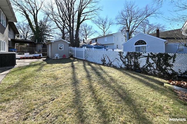 view of yard featuring an outbuilding, central AC, a storage shed, and a fenced backyard