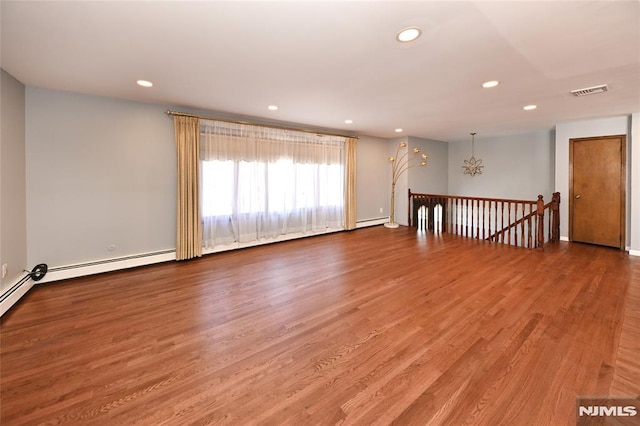 spare room with a baseboard heating unit, a notable chandelier, recessed lighting, and wood finished floors