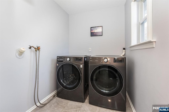 washroom with baseboards, independent washer and dryer, and laundry area