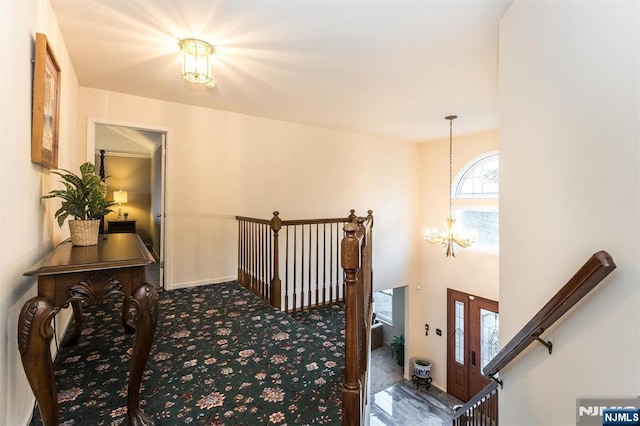 hallway with a notable chandelier and carpet floors