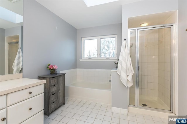 full bathroom with vanity, a skylight, a shower stall, tile patterned floors, and a bath