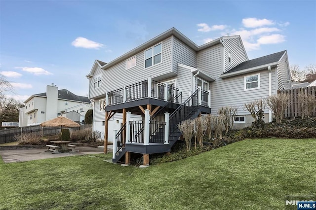 rear view of property featuring fence, a lawn, stairs, and a patio area