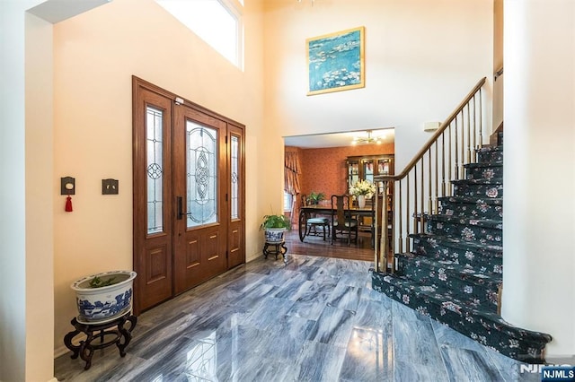 entrance foyer with stairway, a high ceiling, and wood finished floors