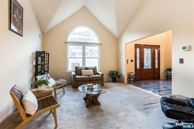 carpeted living area featuring baseboards and high vaulted ceiling