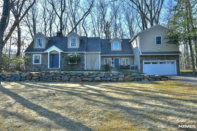 view of front of home featuring stone siding, an attached garage, driveway, and a front lawn