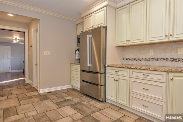 kitchen featuring backsplash, crown molding, baseboards, cream cabinets, and stainless steel appliances