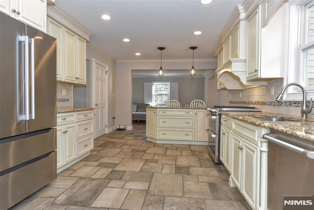 kitchen with cream cabinets, a peninsula, stainless steel appliances, and a sink