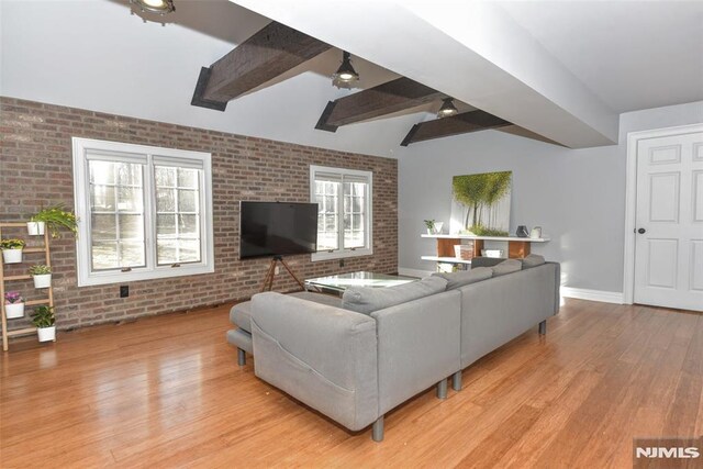 living area featuring baseboards, light wood-style floors, brick wall, and a ceiling fan