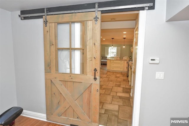 doorway featuring baseboards, stone finish flooring, and a barn door