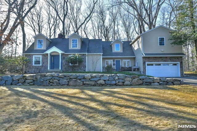 view of front of home with a front yard, a chimney, driveway, stone siding, and an attached garage