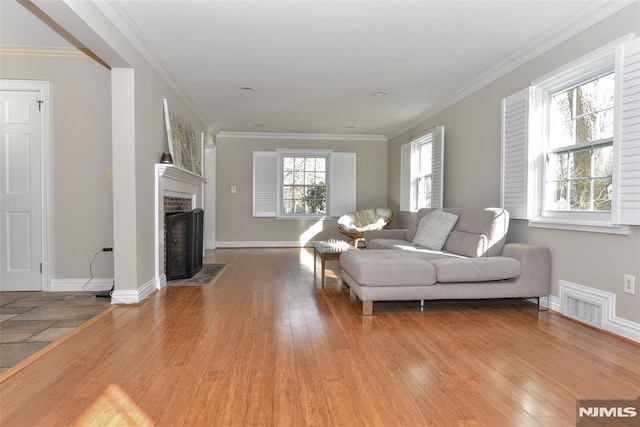 living room featuring visible vents, crown molding, baseboards, light wood-type flooring, and a fireplace