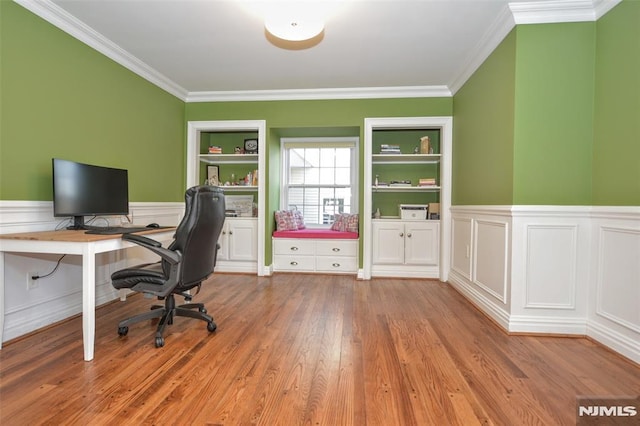 unfurnished office featuring built in features, crown molding, a wainscoted wall, and wood finished floors