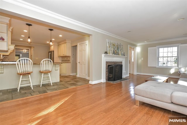 living area with baseboards, light wood-style flooring, recessed lighting, a fireplace, and crown molding