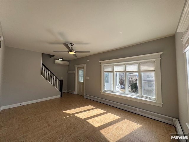 unfurnished living room featuring a wall unit AC, stairway, baseboards, ceiling fan, and a baseboard heating unit