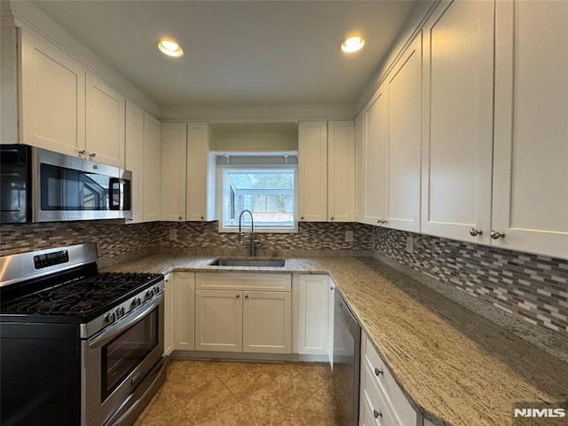 kitchen featuring a sink, light stone counters, backsplash, and appliances with stainless steel finishes