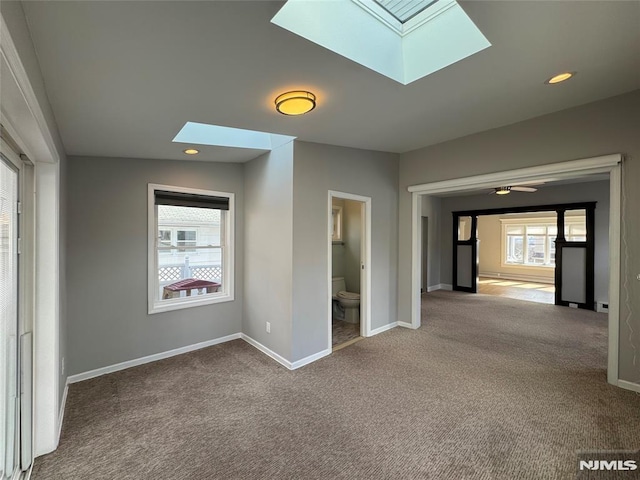 carpeted empty room with recessed lighting, a skylight, and baseboards