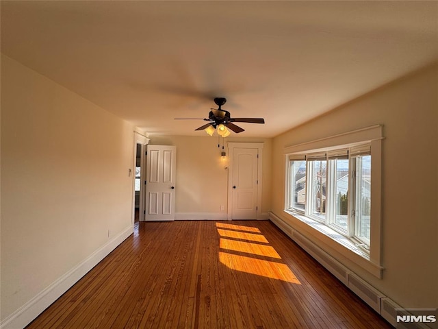 unfurnished living room with a ceiling fan, baseboards, and dark wood-style flooring