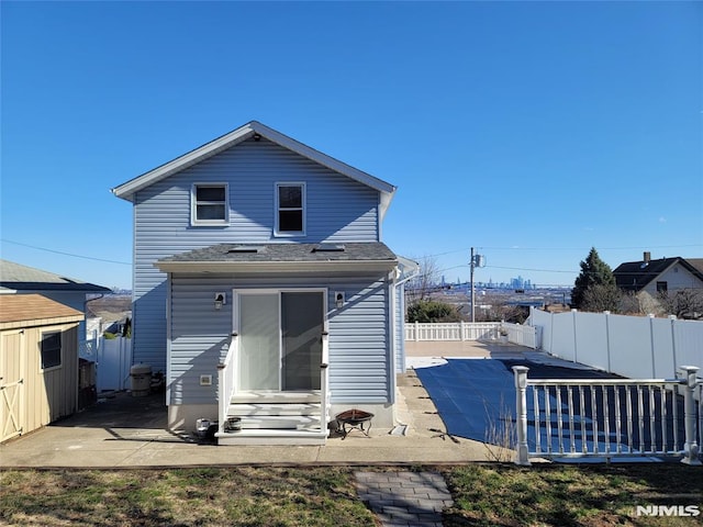 back of property with entry steps, a fenced backyard, an outbuilding, a storage unit, and a patio