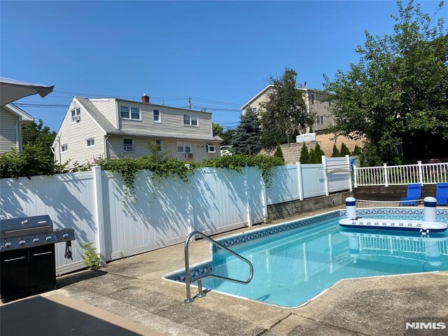 view of pool featuring a patio area, area for grilling, a fenced in pool, and a fenced backyard