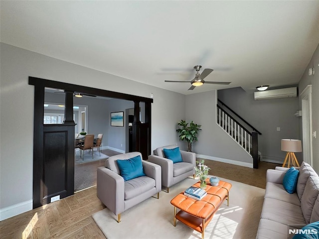 living area featuring stairway, ceiling fan, an AC wall unit, and baseboards