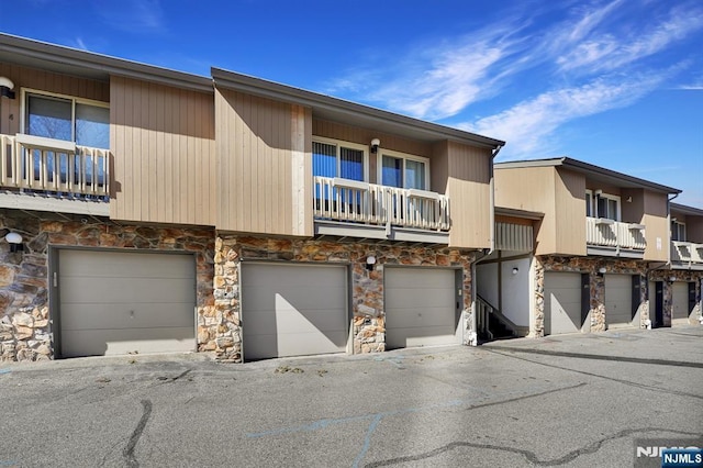 townhome / multi-family property with a garage and stone siding