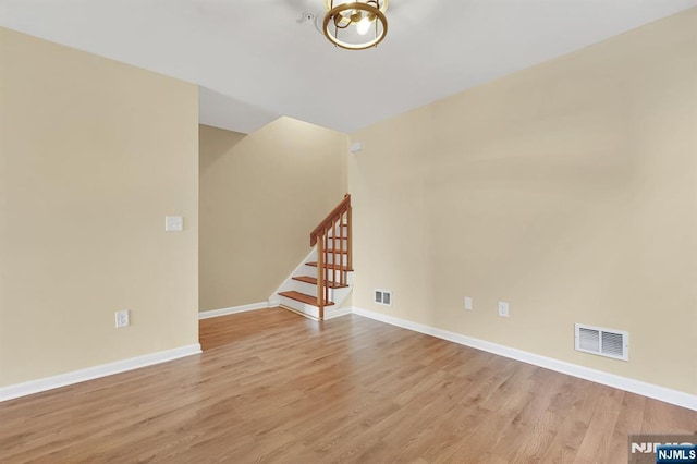 unfurnished room featuring visible vents, light wood-style flooring, stairway, and baseboards