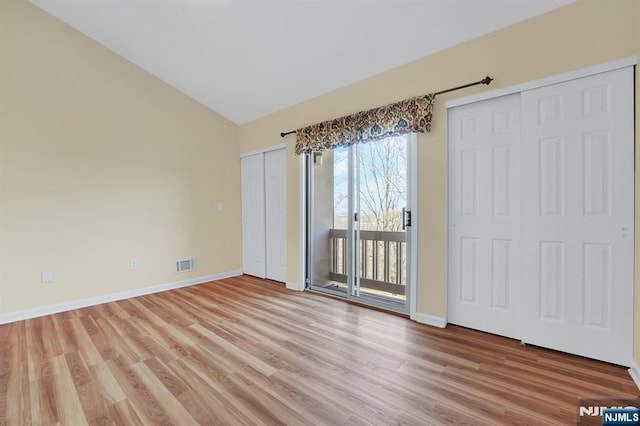 interior space featuring visible vents, baseboards, light wood-type flooring, and lofted ceiling