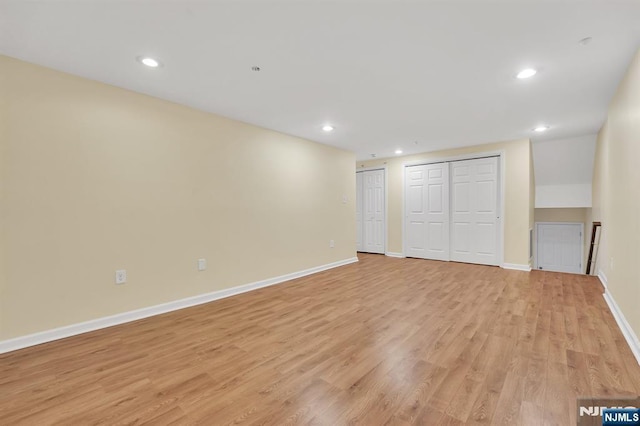 unfurnished bedroom with recessed lighting, light wood-type flooring, baseboards, and two closets