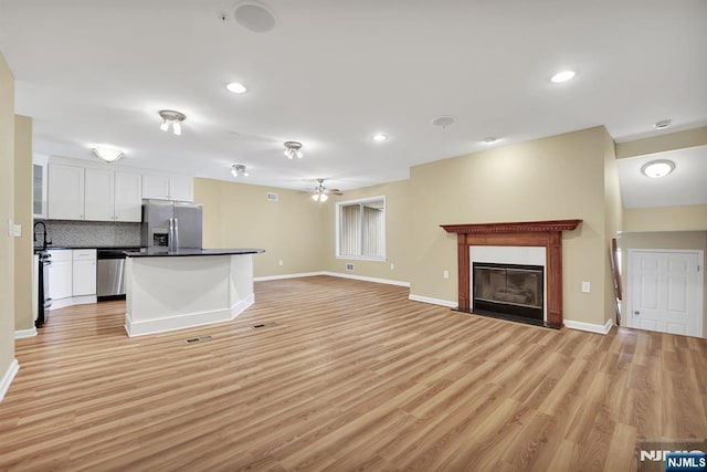 kitchen featuring stainless steel appliances, dark countertops, open floor plan, and white cabinets