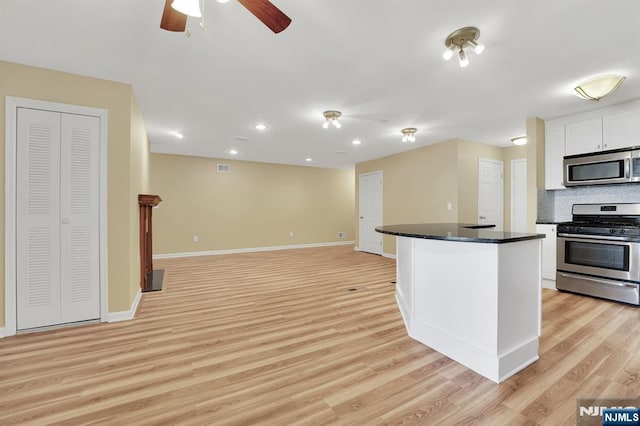 kitchen featuring stainless steel appliances, dark countertops, white cabinets, and light wood finished floors