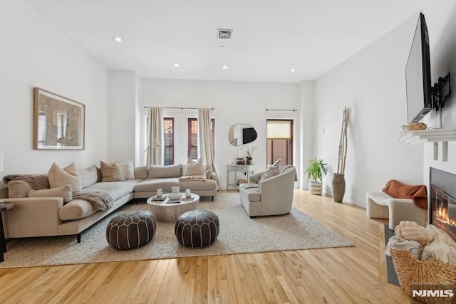 living room with a glass covered fireplace, recessed lighting, visible vents, and hardwood / wood-style flooring