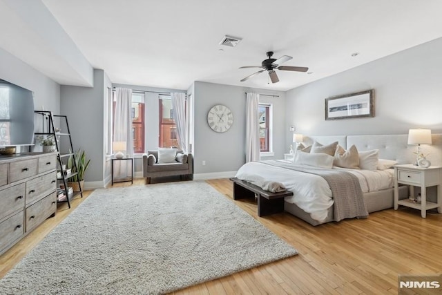 bedroom featuring a ceiling fan, light wood-style floors, visible vents, and baseboards