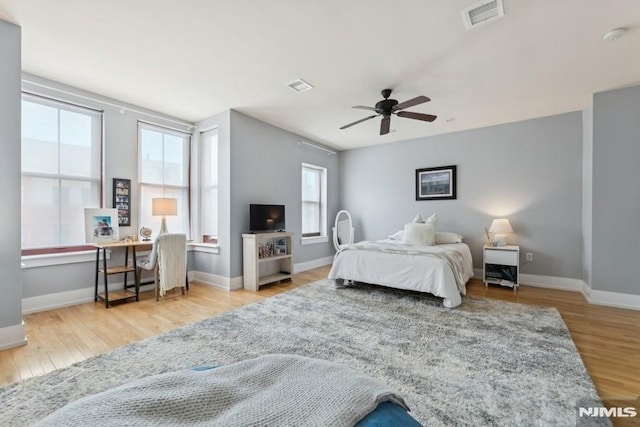 bedroom with visible vents, multiple windows, and wood finished floors