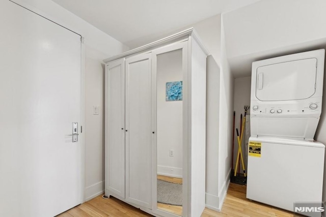 laundry area with laundry area, stacked washer / drying machine, and light wood-type flooring