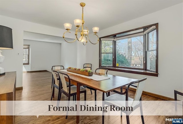 dining area with baseboards, a notable chandelier, and wood finished floors