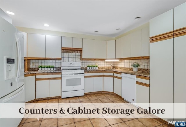 kitchen featuring tasteful backsplash, light tile patterned floors, white cabinets, white appliances, and a sink