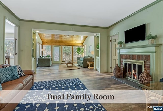 living area with lofted ceiling, ornamental molding, a fireplace, wooden ceiling, and wood finished floors