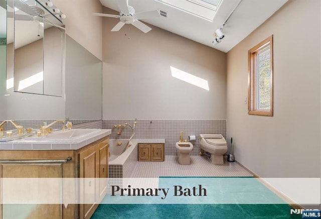 bathroom featuring a bidet, a skylight, track lighting, a garden tub, and toilet