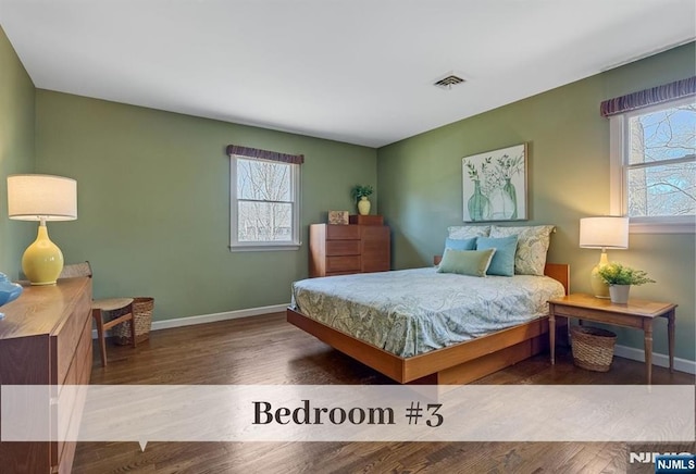 bedroom with multiple windows, wood finished floors, and visible vents