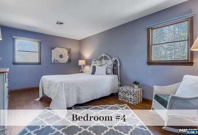 bedroom featuring visible vents, baseboards, and wood finished floors