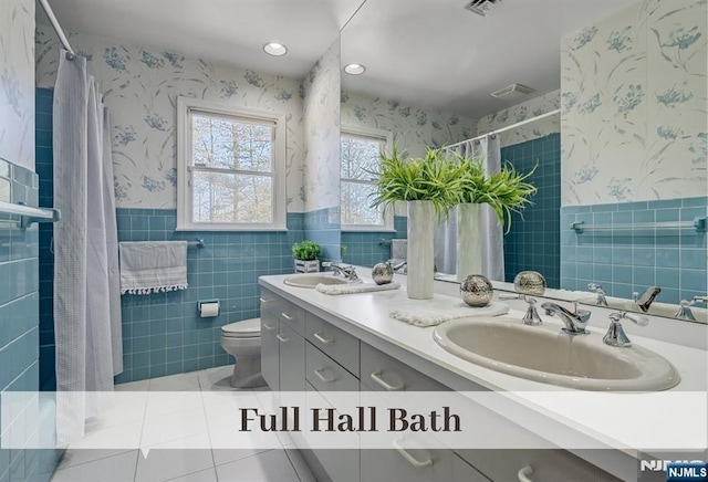 full bath featuring a sink, wainscoting, and wallpapered walls