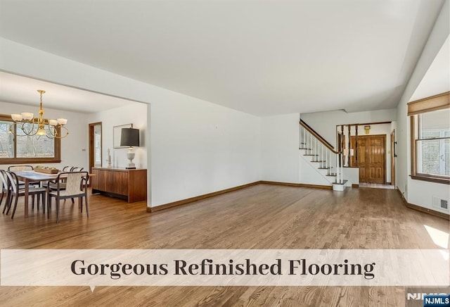 living room with baseboards, stairs, an inviting chandelier, and wood finished floors