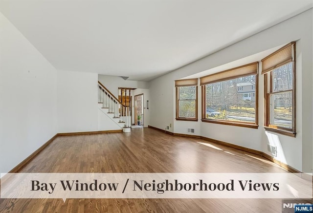 interior space featuring stairs, wood finished floors, visible vents, and baseboards