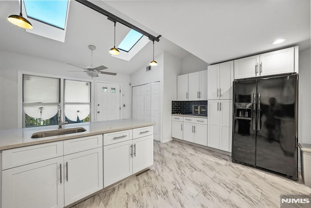 kitchen featuring lofted ceiling with skylight, black fridge with ice dispenser, white cabinets, and a sink